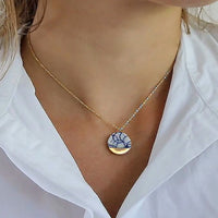 Handmade white and blue porcelain necklace inspired by Delftware tradition. A contemporary ceramic jewelry piece crafted in Delft, The Netherlands, finished with 24k gold details. Elegant, lightweight and designed as a timeless gift for special occasions and 18th wedding anniversaries.